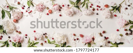 Summer fruit and flowers layout. Flat-lay of white and pink peony flowers, cherries, strawberries and peaches over plain white background, top view, copy space