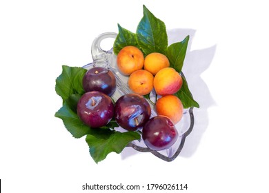 Summer Fruit, Plums And Apricots, With Plum And Apricot Leaves In A Glass Leaf Shape Bowl, Isolated On A White Background. 