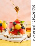 Summer fruit salad with red and yellow watermelon, blueberries, feta cheese and pistachios in glass. Selective focus