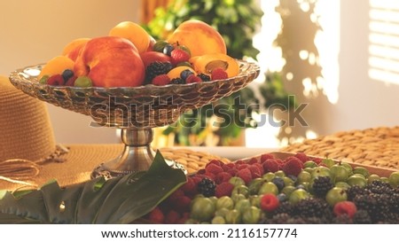 Summer fruity berry background. Table with berries and fruits. Summer breakfast, vacation, morning, sun. Berries, raspberries, blackberries, gooseberries. Vase with berries and fruits. 