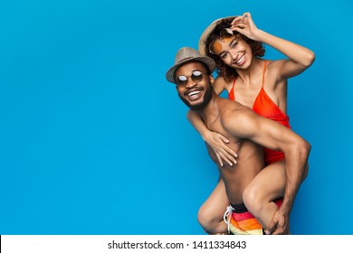 Summer Fun. African American Couple Fooling, Man Piggybacking His Girlfriend, Blue Studio Background, Empty Space