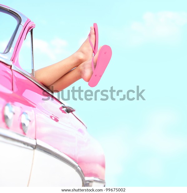 Summer fun vintage car. Legs\
showing from pink vintage retro car. Freedom, travel and vacation\
road trip concept lifestyle image with woman and copy space on blue\
sky.