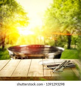 Summer Garden Background With Grill And Wooden Table Of Free Space For Your Decoration. 