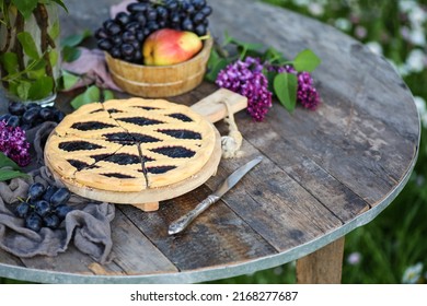 Summer garden. A bouquet of purple lilacs in a vase, a cake with jam on an old wooden table. Fresh fruits and berries, grapes, pears. Outdoor, sun. Rustic. Background image, copy space - Powered by Shutterstock