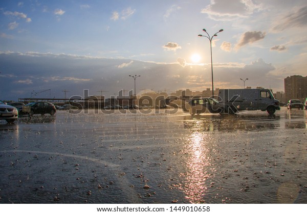 Summer heavy rain in the city. Rain and sun.\
Rain bubbles on asphalt. Cars in the\
rain