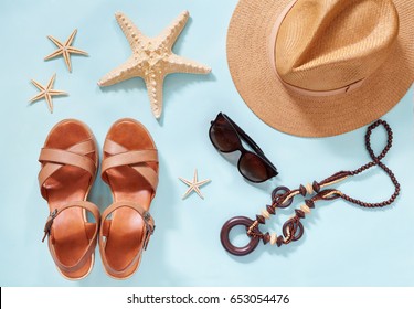 Summer Holiday Background, Flat Lay Beach Women's Accessories: Straw Hat, Bracelets, Leather Sandals, Sun Glasses, Beads And Sea Stars On Blue Table. Vacation And Travel Items. Top View.