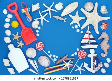 Summer holiday beach and seaside items and symbols with seashells, toys, rock candy and suntan protection lotion. Summer holiday themed concept on blue background with copy space. 
