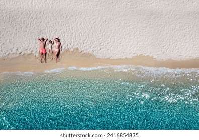 Summer holiday concept with a happy family lying on a beautiful beach with emerald sea, Cyclades, Greece - Powered by Shutterstock