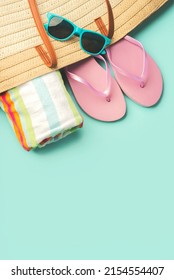 Summer holiday concept.Top view of beach bag with flip flops,beach towel,sunglasses and space for text over blue background