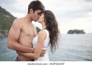 Summer, holiday and couple kiss by sea in vacation, water and outdoor for date in nature for romance. Partners, woman and man together to travel, journey and adventure in ocean for love with hug - Powered by Shutterstock