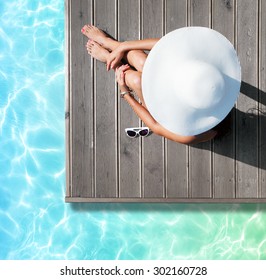 Summer Holiday Fashion Concept - Tanning Woman Wearing Sun Hat At The Pool On A Wooden Pier View From Above