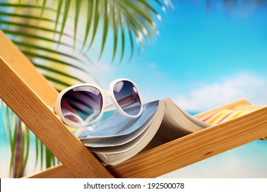 Summer holiday setting with book on beach chair 