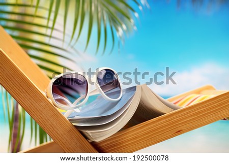 Summer holiday setting with book on beach chair 