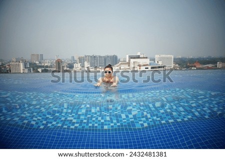Summer holiday Young asian Beautiful woman relaxing in swimming pool at spa resort. Beautiful tropical beach front hotel resort in swimming pool