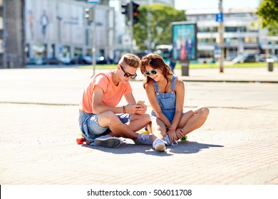 Summer Holidays, Extreme Sport And People Concept - Happy Teenage Couple With Short Modern Cruiser Skateboards On City Street With Smartphone