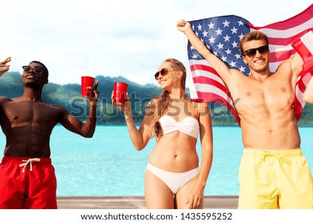summer, holidays and people concept - group of happy friends with flag and non alcoholic drinks celebrating american independence day and party over tropical beach background in french polynesia