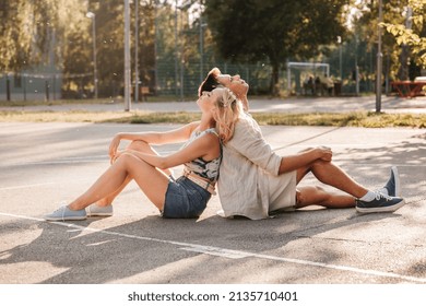 Summer Holidays And People Concept - Happy Young Couple Sitting Back To Back On Basketball Playground