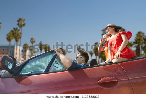 summer holidays, road trip and travel concept\
- happy friends driving in convertible car over venice beach\
background in california