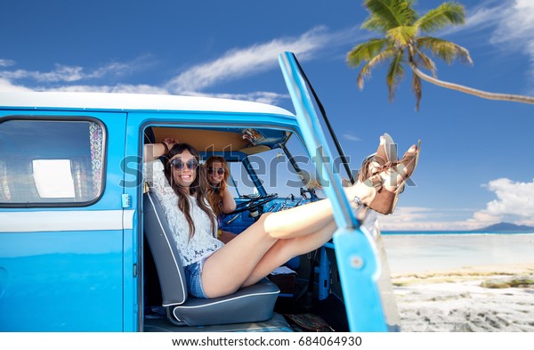 summer holidays, road trip, travel and people\
concept - smiling young hippie women resting in minivan car over\
tropical beach\
background
