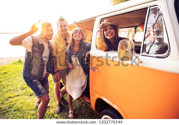 Summer
holidays, road trip, vacation, travel and people concept - smiling
young hippie friends having fun over minivan
car