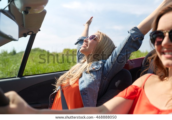 summer holidays,\
road trip, vacation, travel and people concept - smiling young\
women driving in in cabriolet\
car