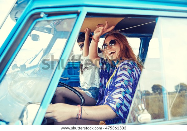 summer holidays, road trip, vacation, travel and
people concept - smiling young hippie women driving minivan car and
showing peace gesture