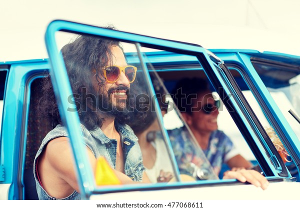 summer holidays, road\
trip, vacation, travel and people concept - smiling young hippie\
friends in minivan car