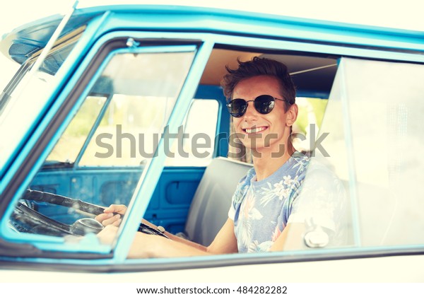 summer holidays,
road trip, vacation, travel and people concept - smiling young
hippie man driving in minivan
car
