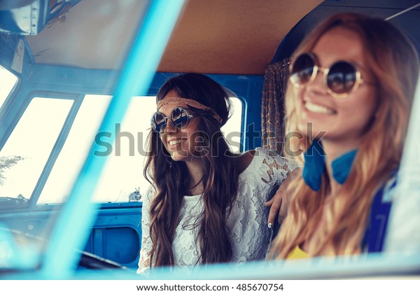 summer\
holidays, road trip, vacation, travel and people concept - smiling\
young hippie women driving in minivan\
car