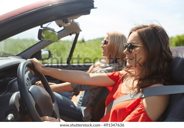 summer holidays,\
road trip, vacation, travel and people concept - smiling young\
women driving in in cabriolet\
car