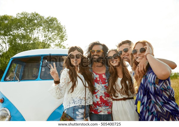 summer holidays, road trip, vacation, travel and\
people concept - smiling young hippie friends over minivan car\
showing peace hand sign