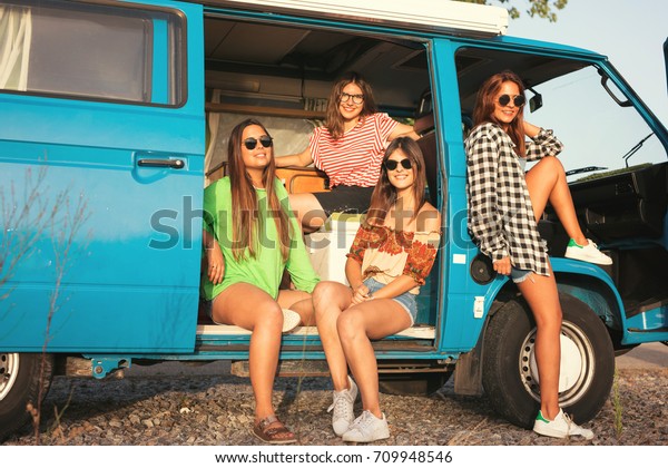 Summer holidays, road trip,
vacation, travel and people concept - smiling young hippie women in
car