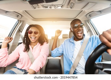 Summer Holidays And Roadtrip Concept. Front View Portrait Of Excited Black Couple In Sunglasses Driving Car, Dancing To Music And Singing Favorite Song, Going On Vacation For Rest And Relax, Sun Flare