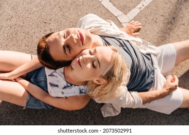 Summer Holidays, Romantic And People Concept - Happy Young Couple Sitting Back To Back On Basketball Playground