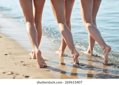 Summer Holidays, Travel, Body Care And People Concept - Close Up Of Happy Young Women Walking And Hugging On Beach From Back