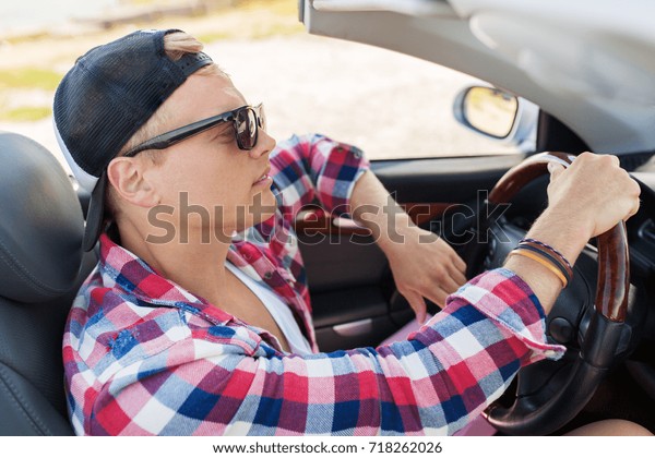 summer holidays, travel, road\
trip and people concept - happy young man driving convertible\
car