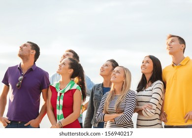 summer, holidays, vacation, happy people concept - group of friends looking up on the beach