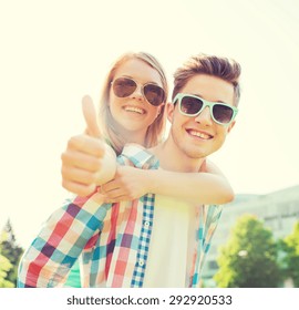 Summer Holidays, Vacation, Love, Gesture And Friendship Concept - Smiling Teen Couple In Sunglasses Having Fun And Showing Thumbs Up In Park