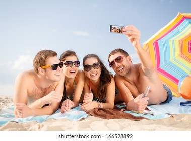 summer, holidays, vacation, technology and happiness concept - group of smiling people in sunglasses taking selfie with smartphone on beach - Powered by Shutterstock