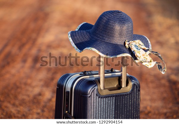 Summer holidays,Suitcase or\
luggage bag with sun hat,Suitcase and hats on the roads of the\
countryside,