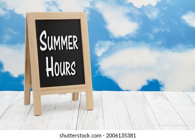 Summer hours sign on standing chalkboard on weathered wood with clear sky - Powered by Shutterstock