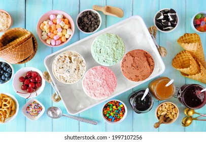 Summer Ice Cream Buffet With A Variety Of Flavors And Sweet Toppings. Overhead View Table Scene On A Blue Wood Background.