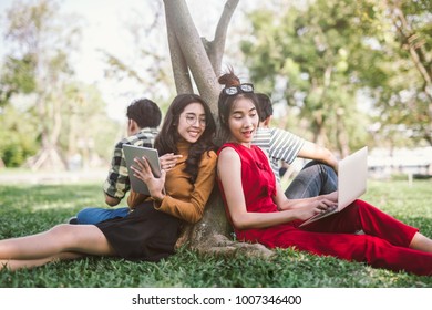 Summer, Internet, Education, Campus And Teenage Concept - Group Of Students Or Teenagers With Laptop And Tablet Computers Hanging Out