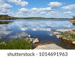 Summer landscape. Bay with reflection of clouds in stone banks. Russia, Karelia, lake Ladoga