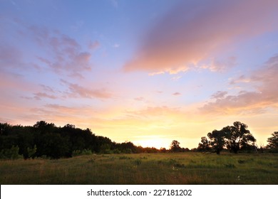 Summer Landscape Beautiful Bright Sunset Over The Meadow And Oak Forest On The Horizon