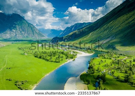 Summer landscape in the Chulyshman mountain valley. Winding mountain river, green alpine meadows and beautiful mountains. Russian nature. Gorny Altai, Siberia