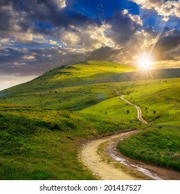 summer landscape. mountain path through the field turns uphill to the sky at sunset