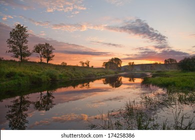 summer landscape pink and orange sunset over the tranquil river and trees on the shore