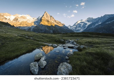 Summer landscape view in Zinal with the Besso mountain relecting in a stream at sunset