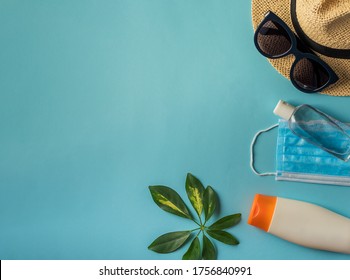Summer layout. Straw hat, protective medical mask, sanitizer and green leaf with copy space. Concept of travel and vacation,Coronavirus,Covid-19,pandemic, global quarantine. Flat lay. Top view